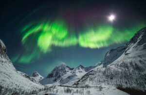 aurora borealis over valley and mountains