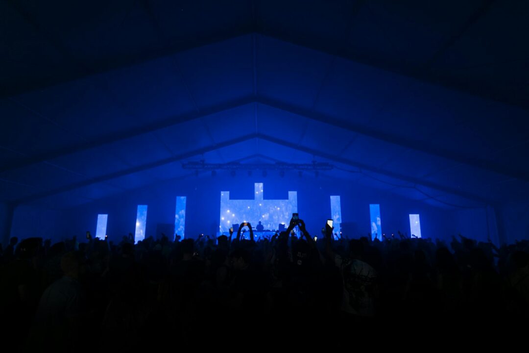 people raising phones in dark room